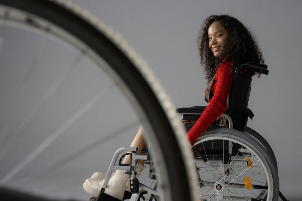 Cheerful girl in a wheelchair smiling with selective focus on a neutral background.